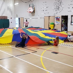 Students participating in a group activity in the Academy International Elementary School gym.